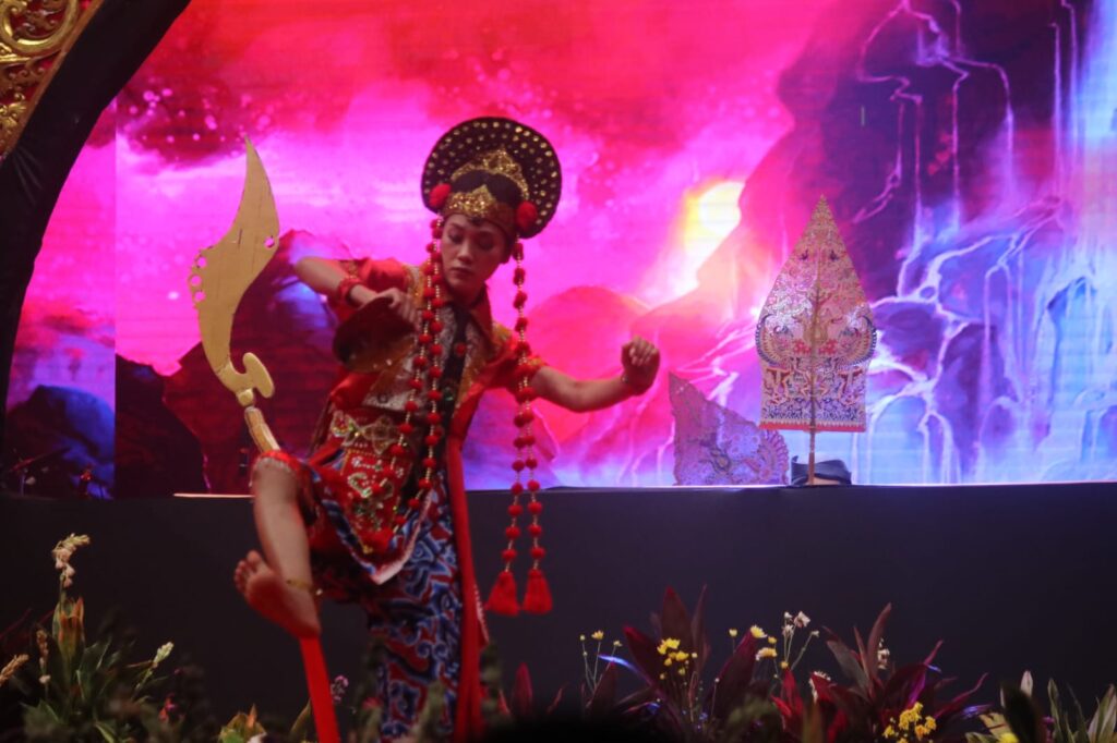 Whatsapp image 20260612 at 14 05 17 1 catrawarta Young dancer in ornate red traditional costume and gold headdress performing a martial arts pose on a colorful stage